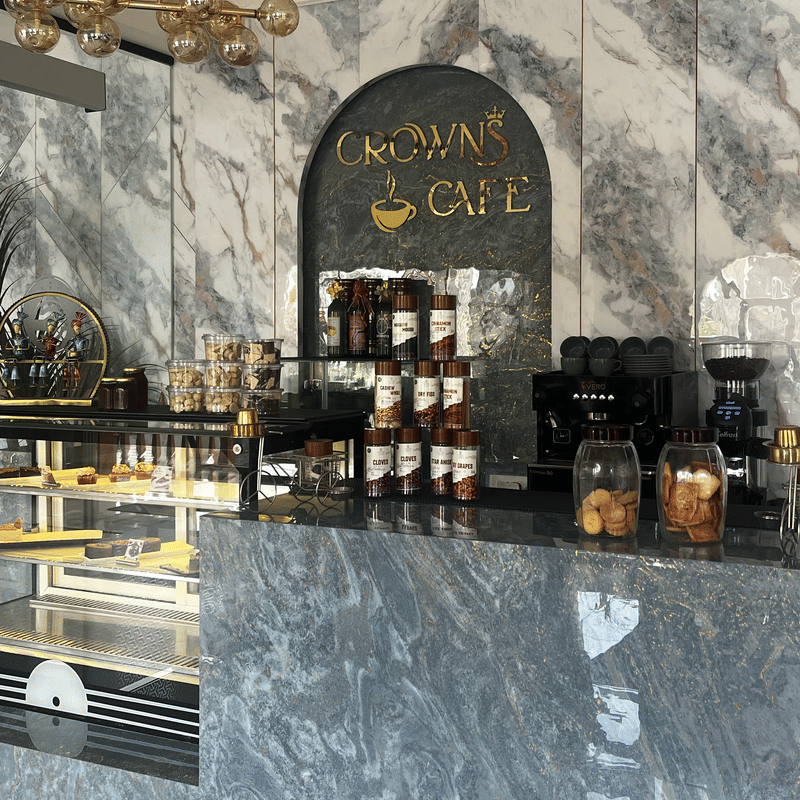 The marble Crown Cafe counter with coffee machines and the gold Crown Cafe sign behind