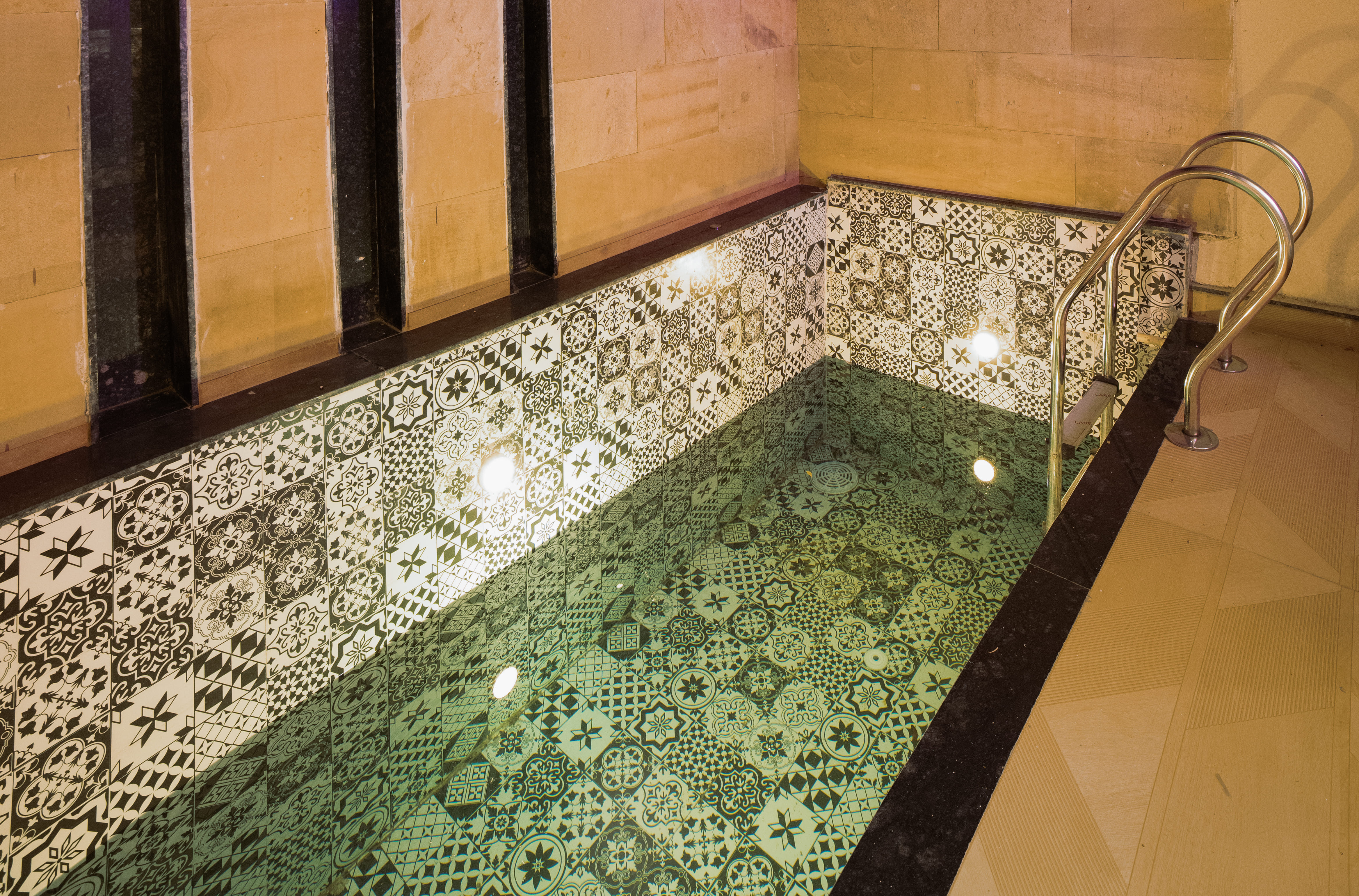 Patterned-tile private plunge pool with a steel railing, lit at night in a Premium Room at Nazaara Hills Retreat, Udaipur