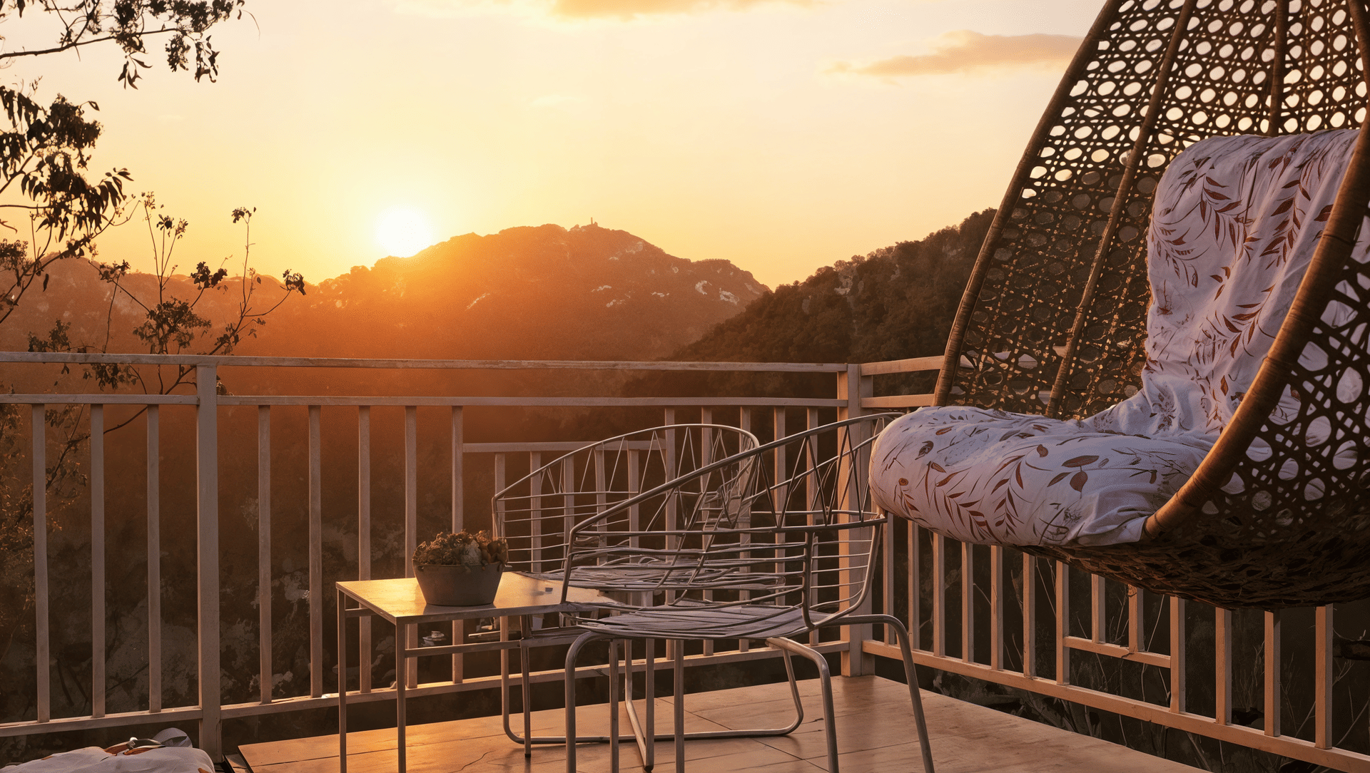 Wide sunset view from a Luxurious Cottage balcony, Nazaara Nature Retreat, forested mountains stretching toward the horizon