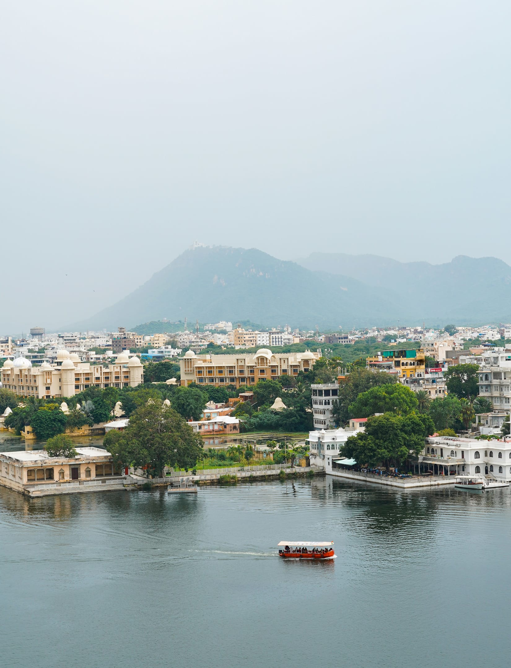 Aerial view of Lake Pichola in Udaipur with island palaces on the water and the City Palace along the shoreline