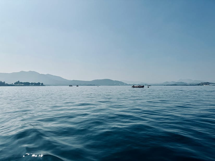 Calm waters of Lake Pichola in Udaipur framed by the Aravalli Hills under a clear sky