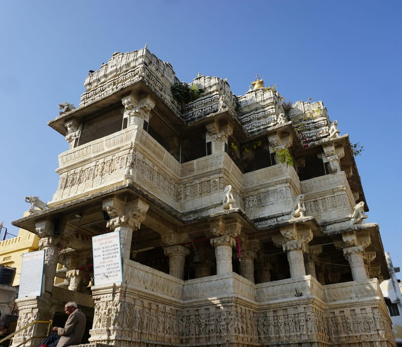 Ornately carved three-storey stone facade of Jagdish Temple in Udaipur rising against a clear blue sky