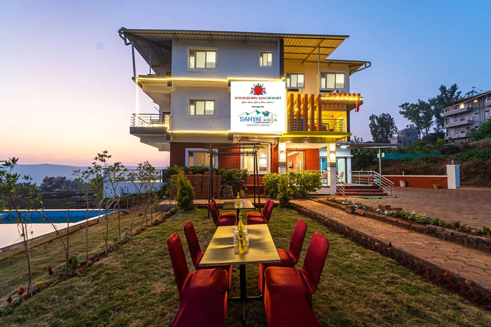 The resort entrance lit up at twilight, with a table and red chairs set on the lawn