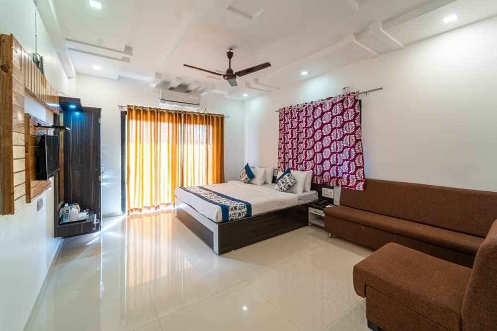 Deluxe Valley View Room with a king bed, a brown sofa and a magenta patterned curtain