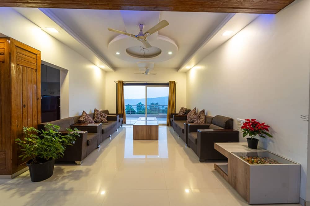 Long lounge with leather sofas facing a glass door with a view of the hills