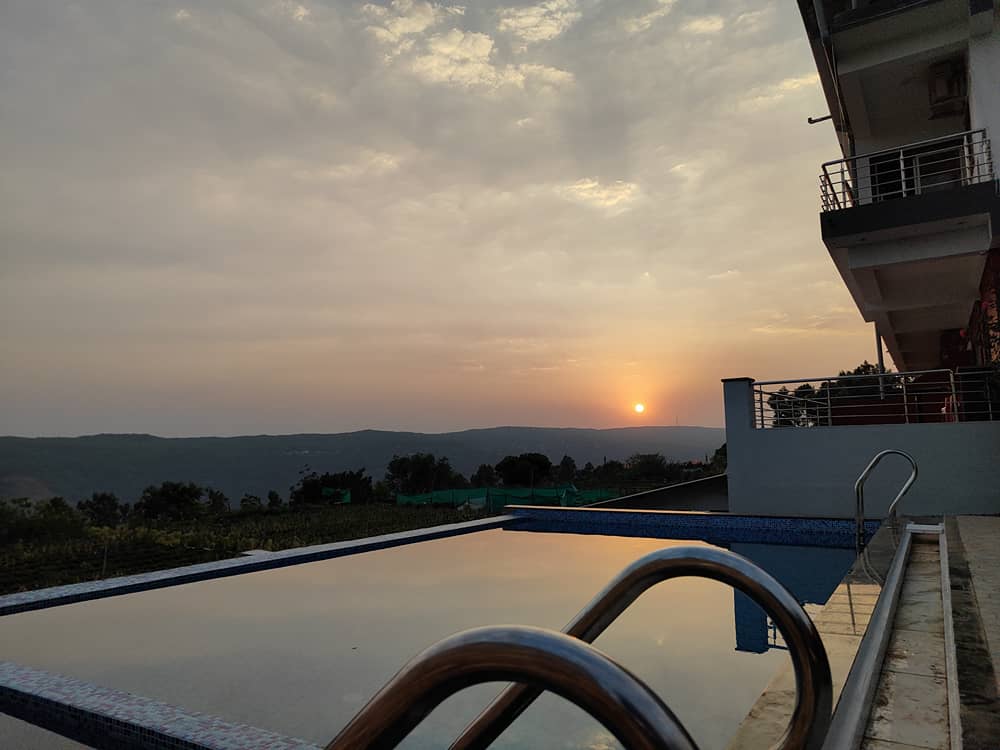 Sun setting over the hills, seen across the edge of the infinity swimming pool