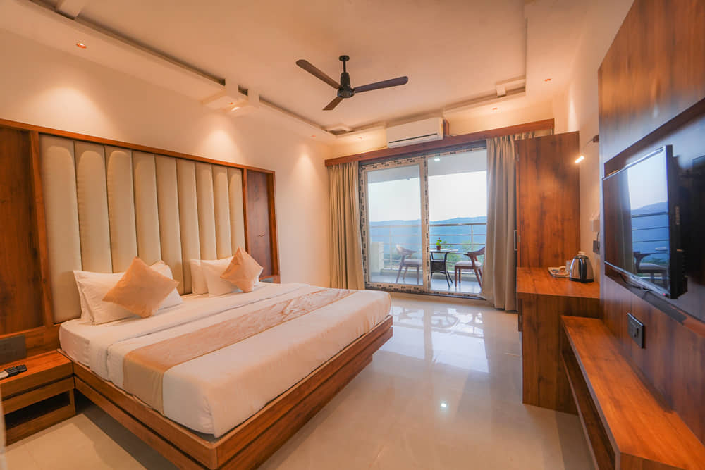 Suite Room with a king bed, wooden furnishings and balcony doors opening to the hills