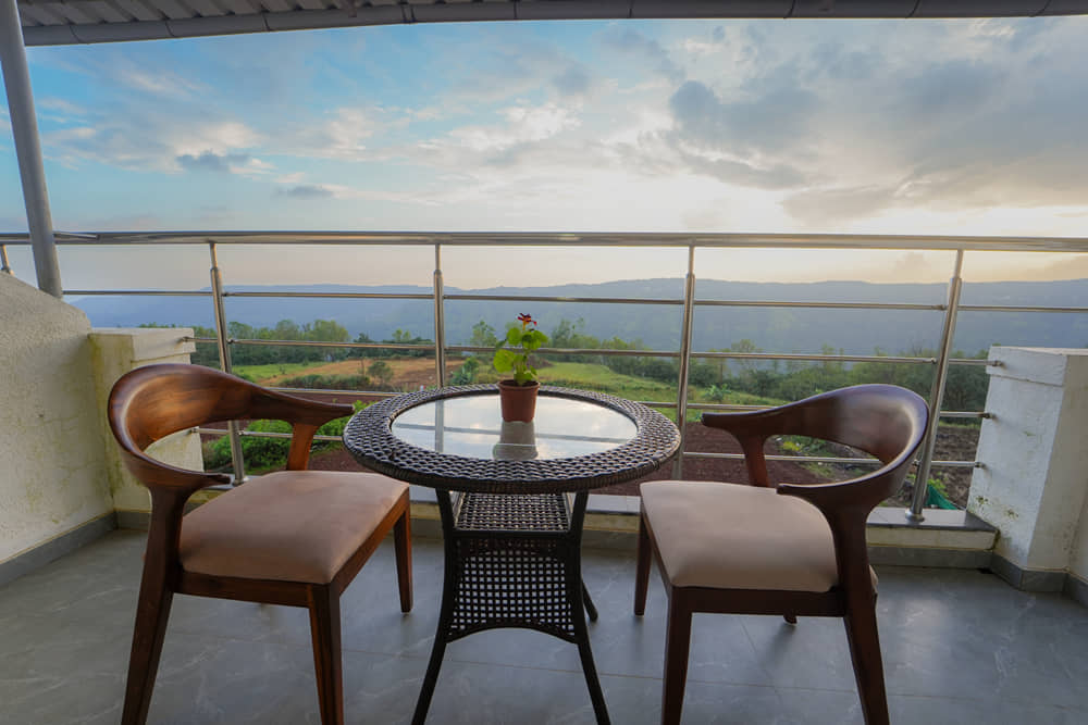Suite Room balcony with a round glass table and two chairs overlooking the valley