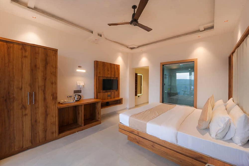 Premium Room with a king bed, a wooden wardrobe, a wall-mounted TV and a ceiling fan