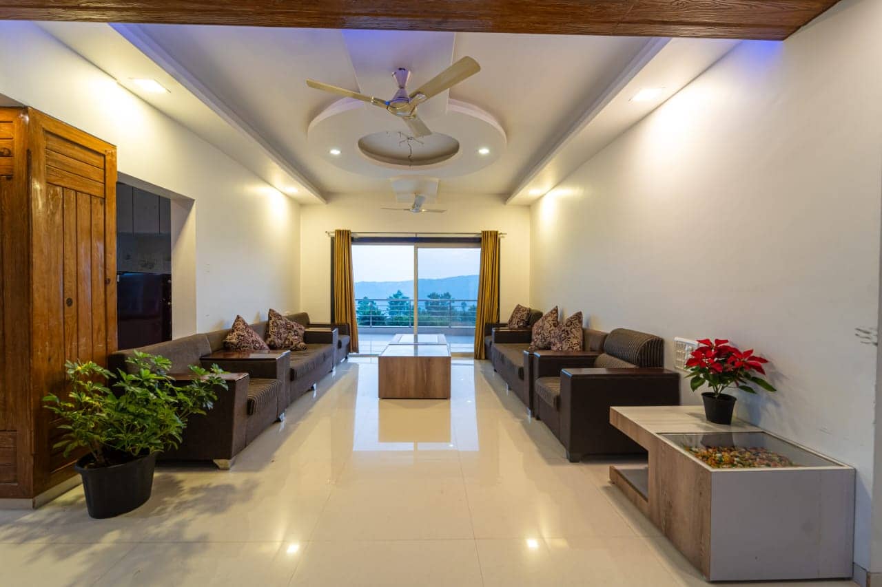 Long lounge with leather sofas facing a glass door with a view of the hills