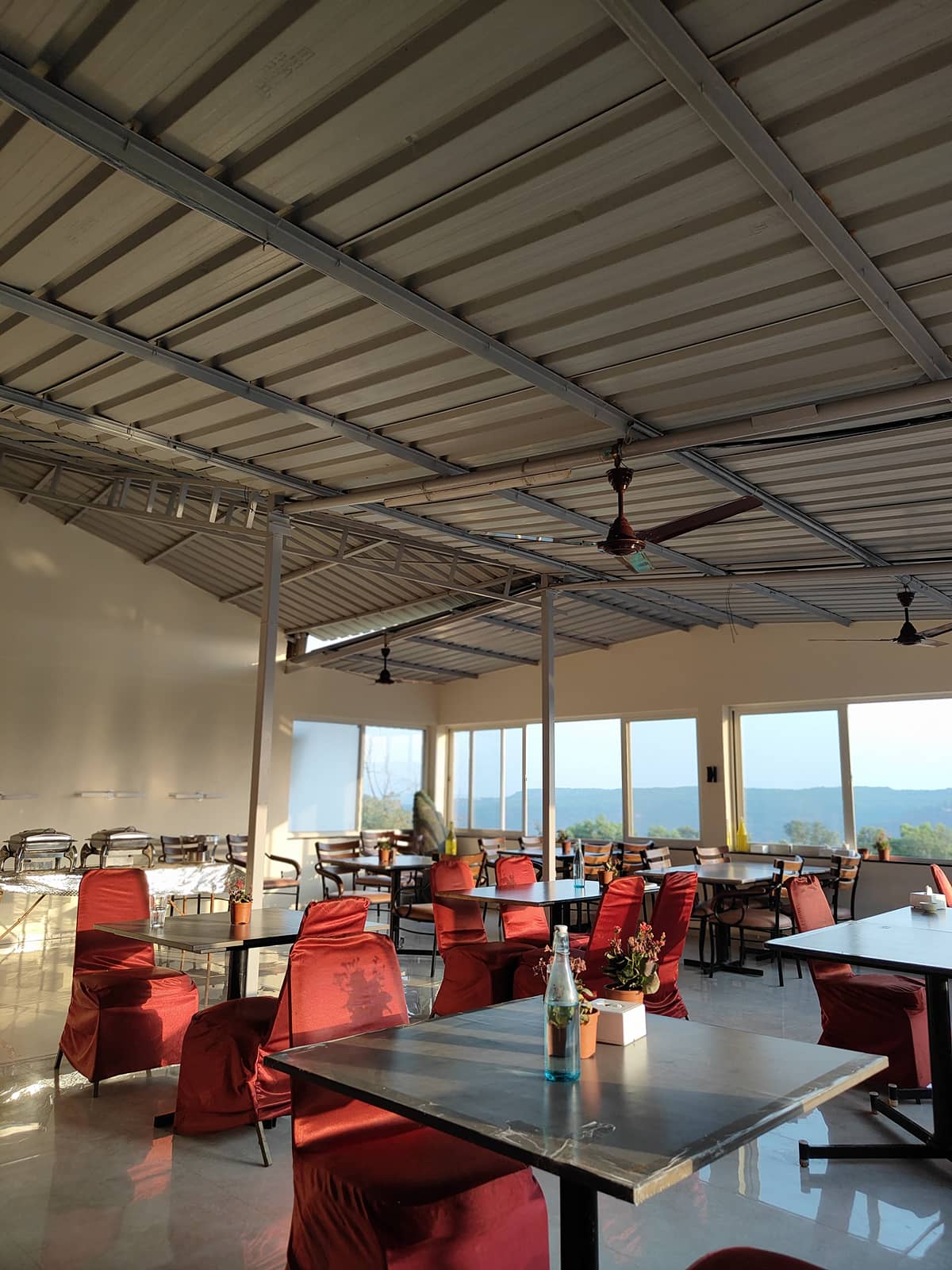 The Sahyagirija restaurant hall with red chairs and tall windows onto the valley
