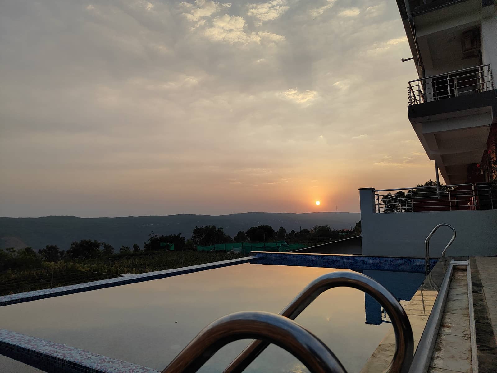Sun setting over the hills, seen across the edge of the infinity swimming pool