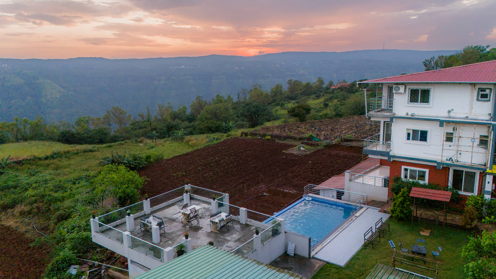 Aerial view of the resort and its pool on the hillside at sunset