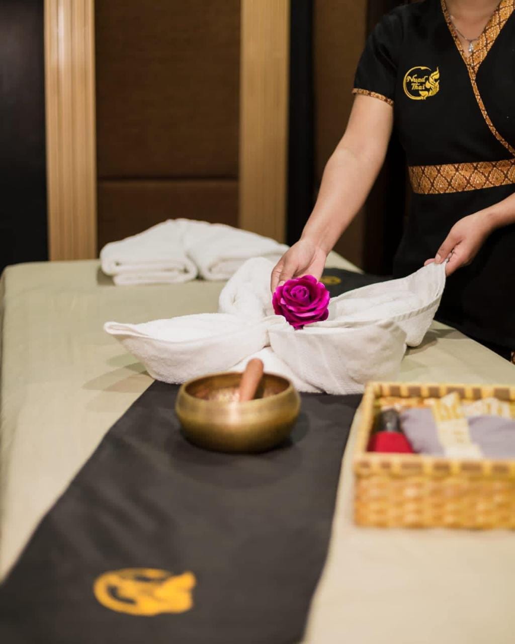 A Nuad Thai therapist laying out a folded towel and singing bowl before a treatment