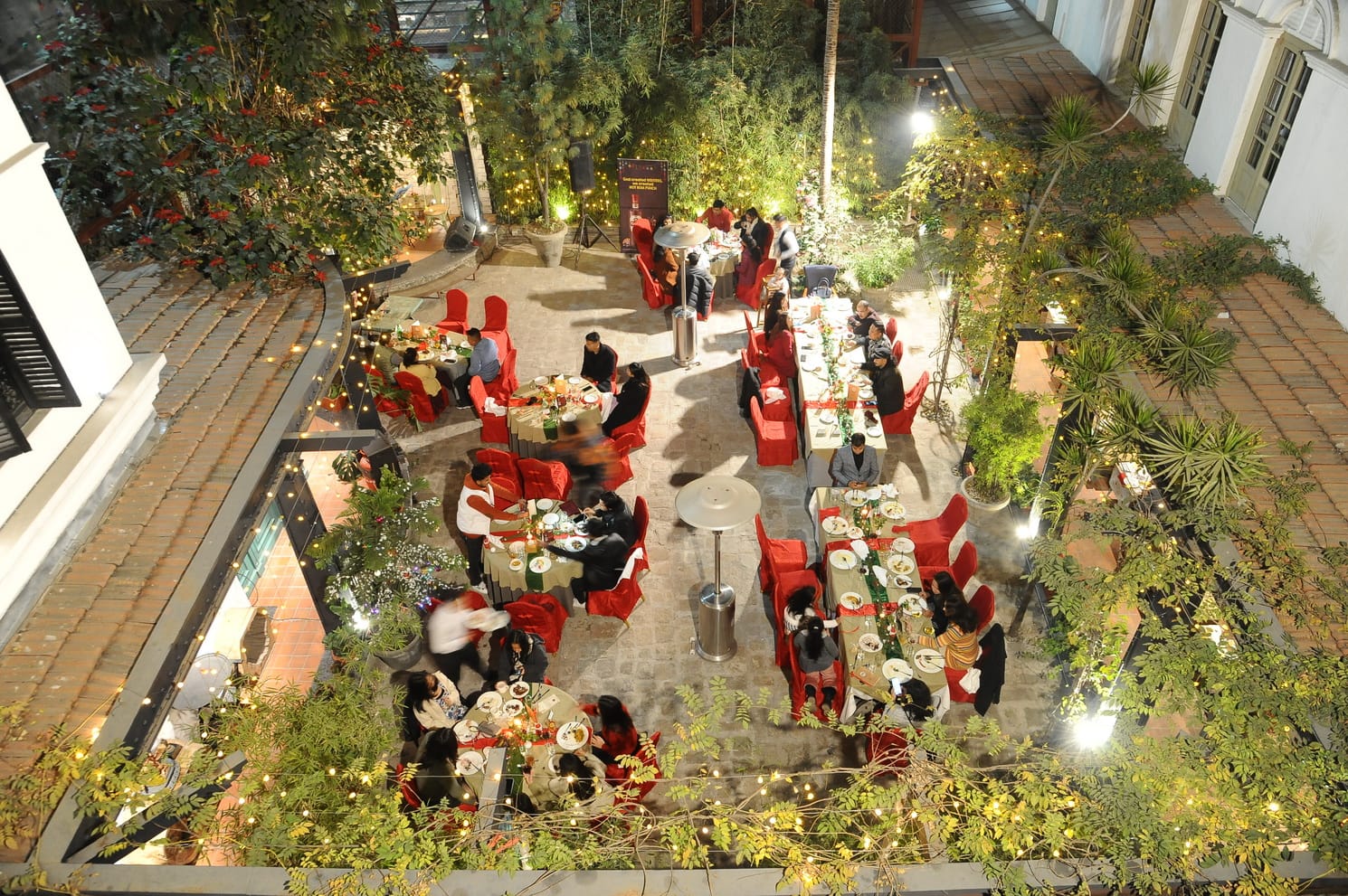 The garden courtyard at Chiya Pasal laid for dinner, tables filling the terrace beneath the trees
