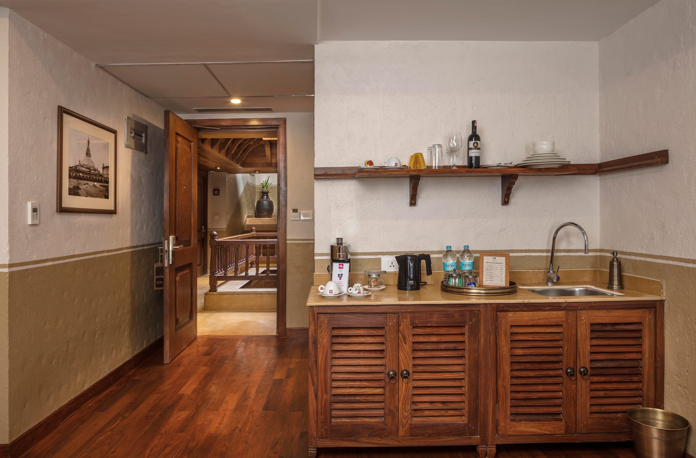 A view of the Executive Suite pantry corridor at Nepali Ghar Hotel, with the illy coffee machine and kettle on the counter, beside the open stairwell landing.