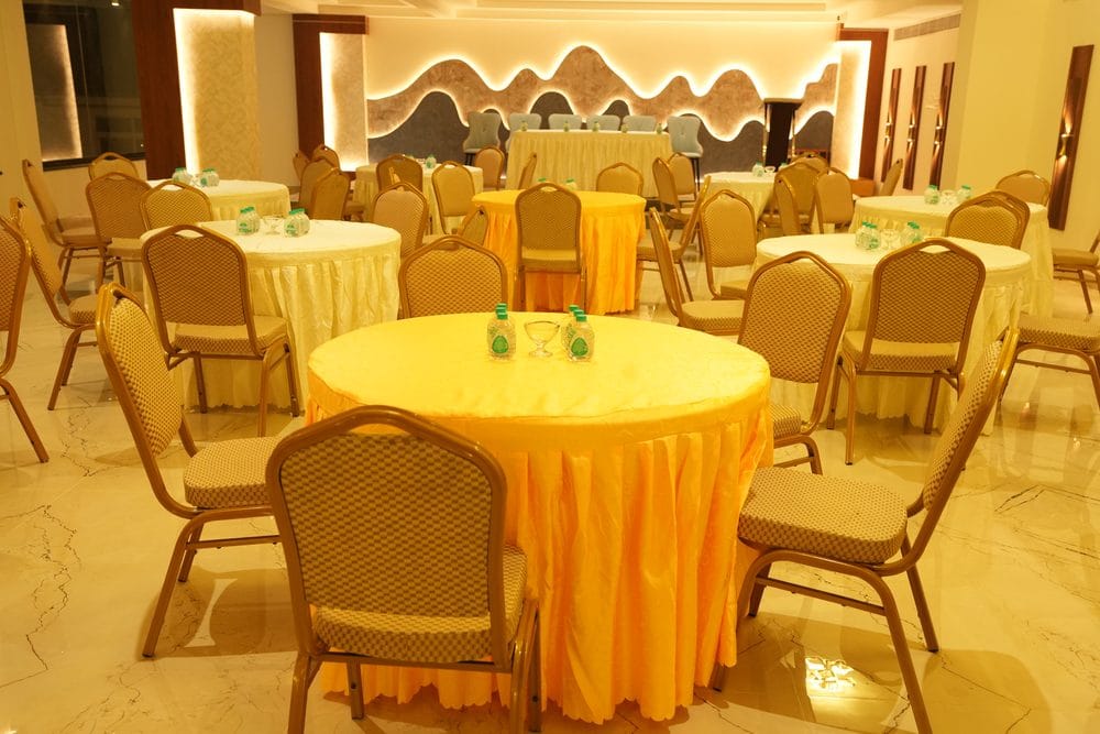 Grand Gathering banquet hall laid with round tables in gold and cream linen, facing the head table