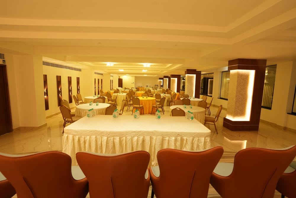 A long skirted head table set in front of rows of round tables in the Grand Gathering hall