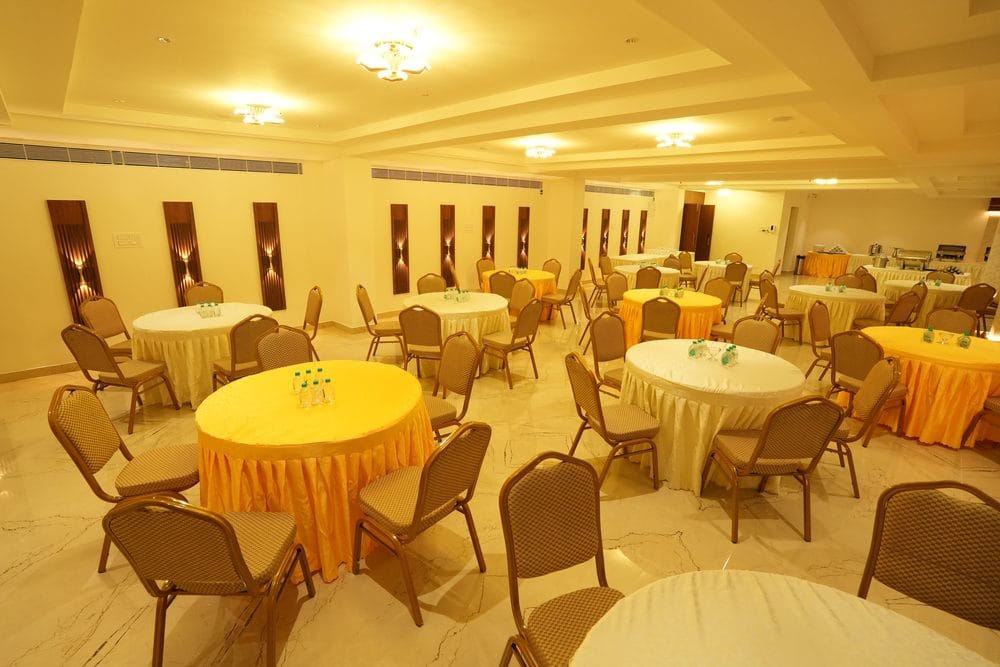 The full Grand Gathering hall laid with round tables in gold and cream, with a buffet line at the far end