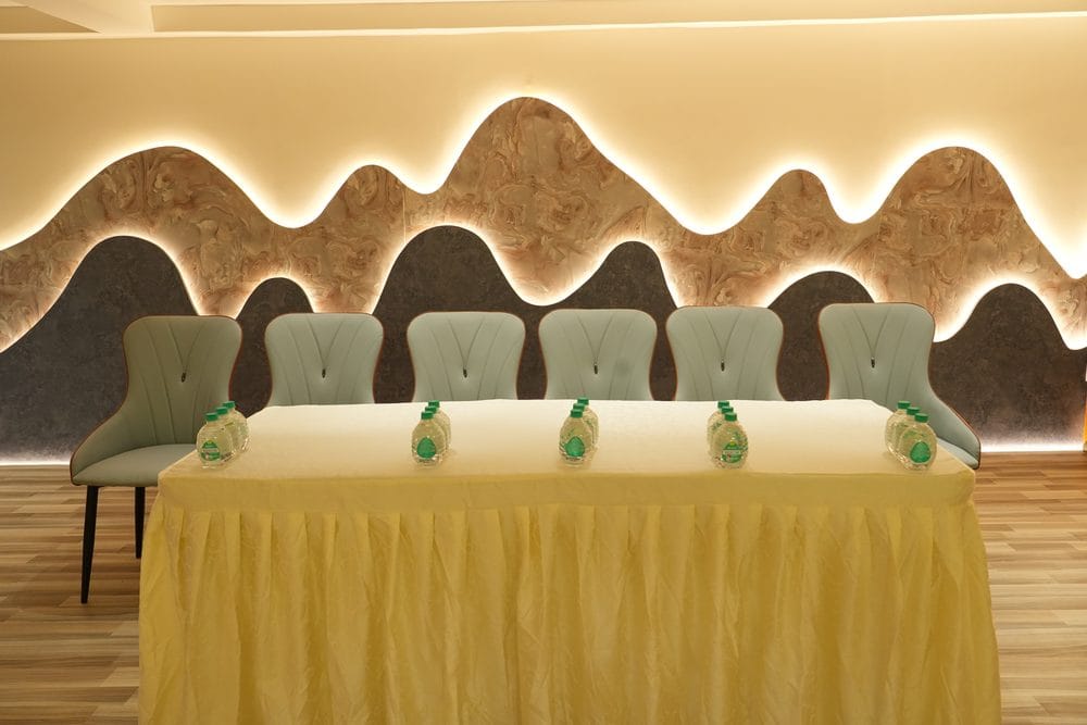 Six chairs behind a skirted head table, set against the backlit sculpted feature wall of the banquet hall