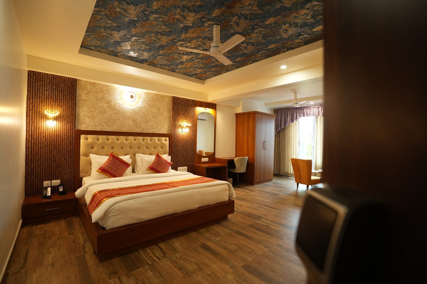 Crown Suite seen from the doorway, with the bed, wardrobe and a seating corner by the window