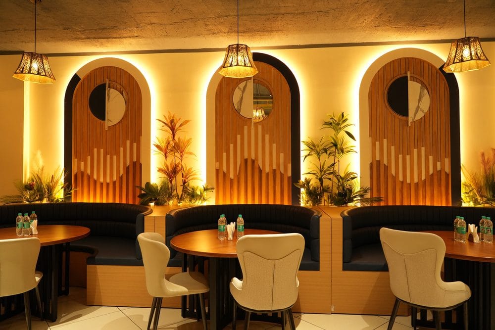 Curved leather booths and round tables set against backlit arched timber screens at Golden Garnish