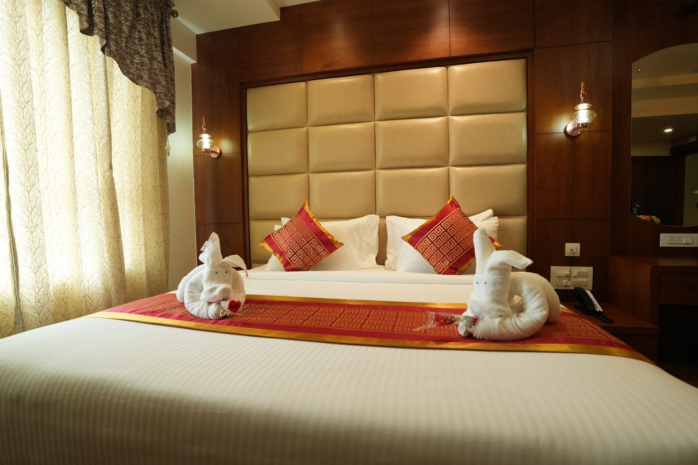 Presidential Suite bed made up for arrival with towel art, beneath a padded headboard and wood panelling