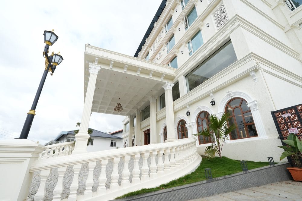 Arched timber windows and a white balustraded terrace running along the front of the building