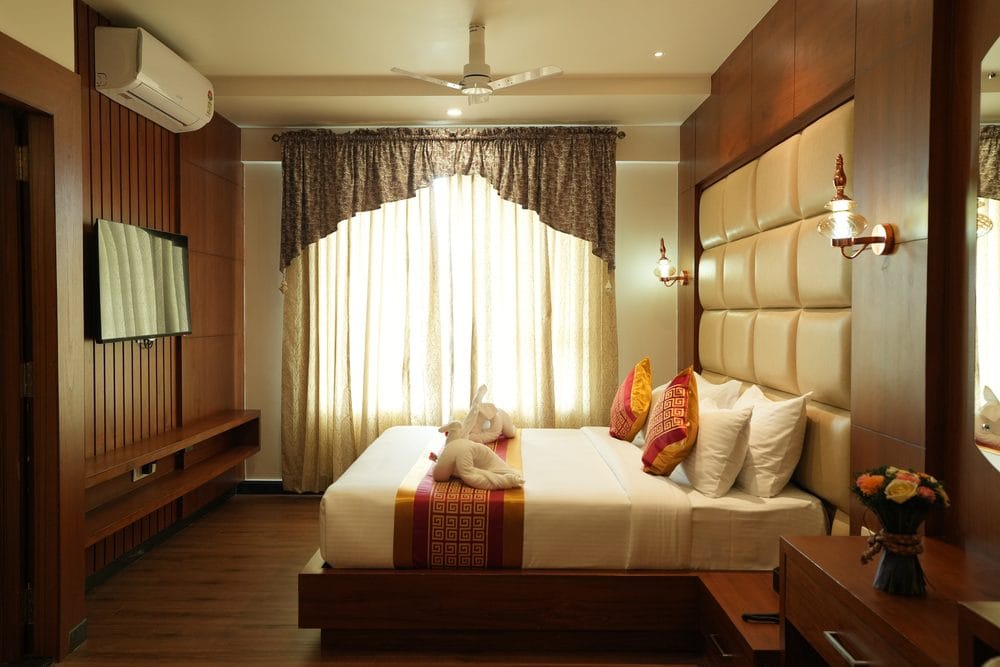 Guest room with a king-size bed, padded headboard and a wood-panelled television wall opposite