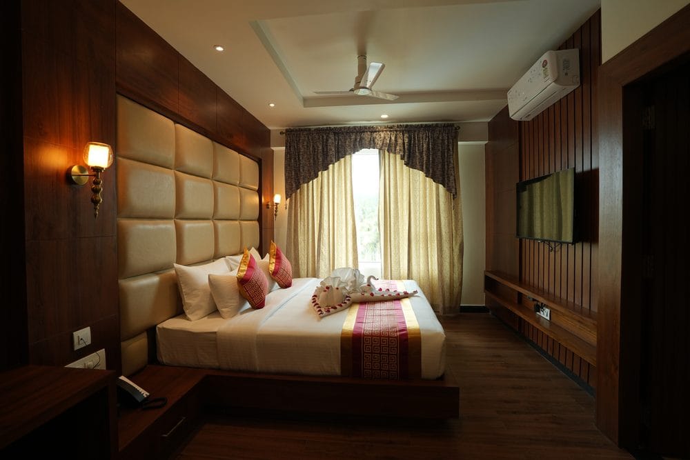 Guest room with a king-size bed, wall lights and a 43-inch television on the panelled wall