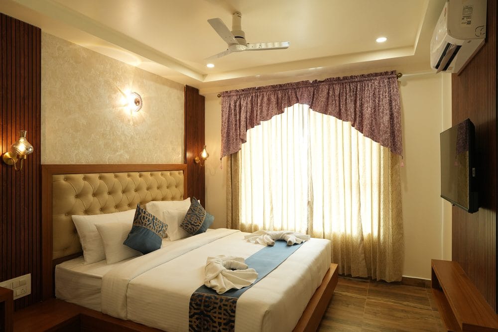Guest room with a tufted headboard, brass wall lights and a full-height curtained window