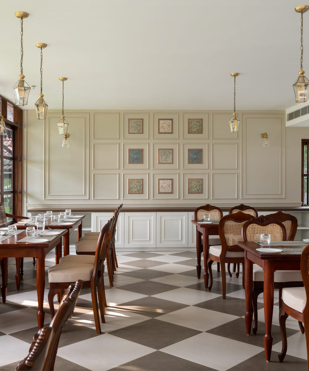 Long dining table set with white linen and place settings under warm pendant lamps at The Lilly's, Sanskreti, Kumbalanghi