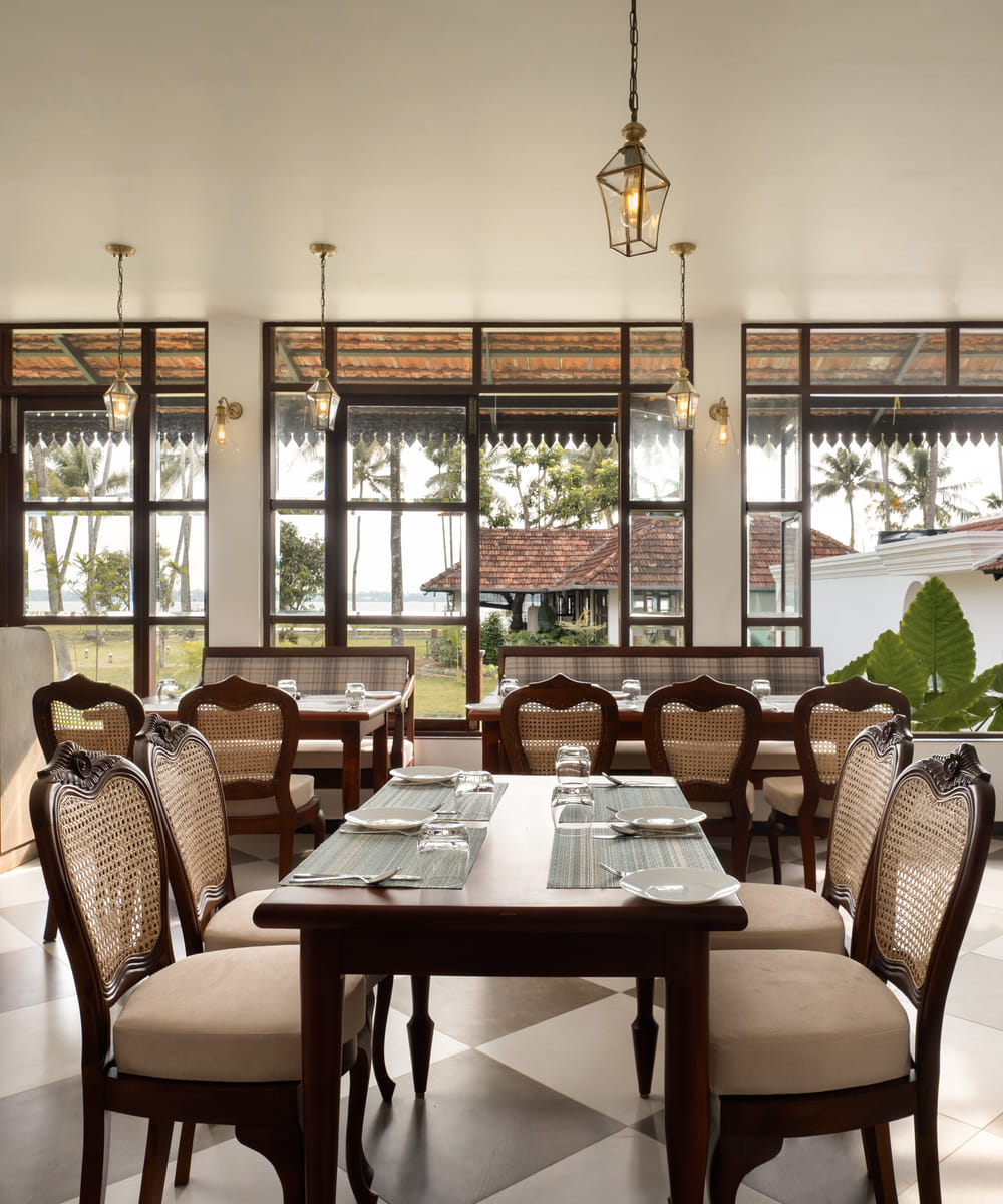 The Lilly's multi-cuisine restaurant with wood tables and chairs beside large windows facing the lake, Sanskreti