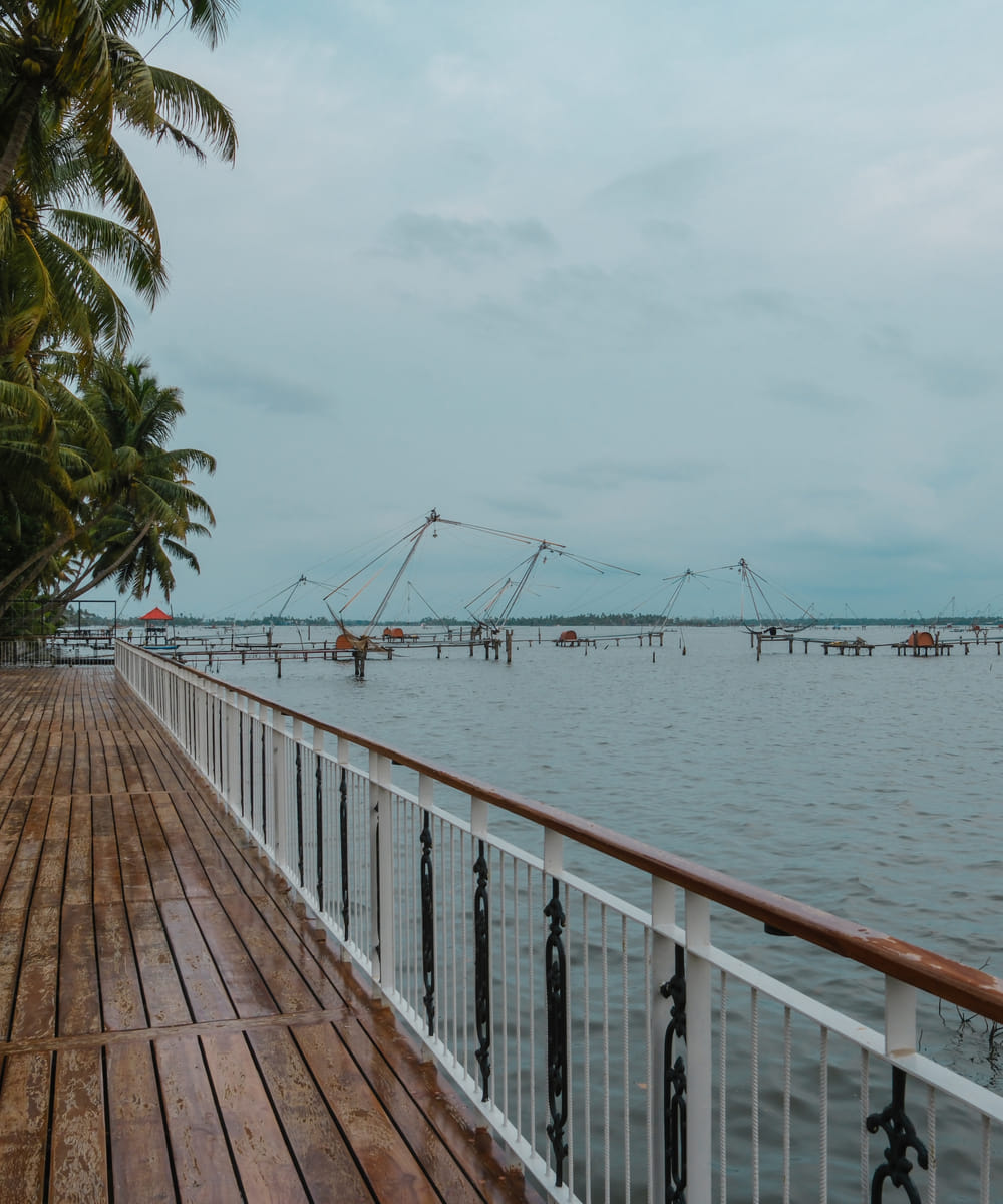 Wooden deck extending over the backwater with a Chinese fishing net and coconut palms along the far shore, Sanskreti, Kumbalanghi