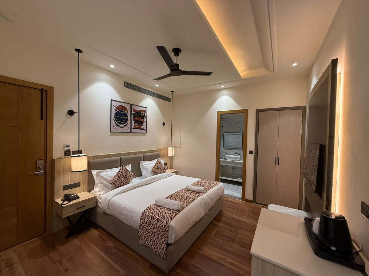 A guest room at Amara Portico, with a patterned runner across the bed, a wall lamp, a ceiling fan