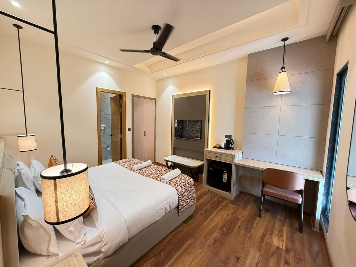 A guest room at Amara Portico, with pendant lamps either side of the bed and a work desk set with a kettle along the far wall