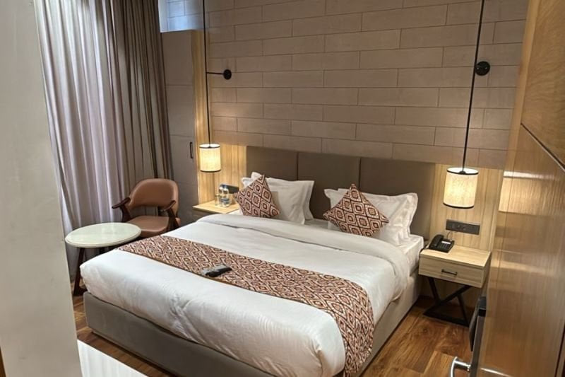 The Deluxe with City View at Amara Portico, with tall reading lamps either side of the bed and an armchair beside the window