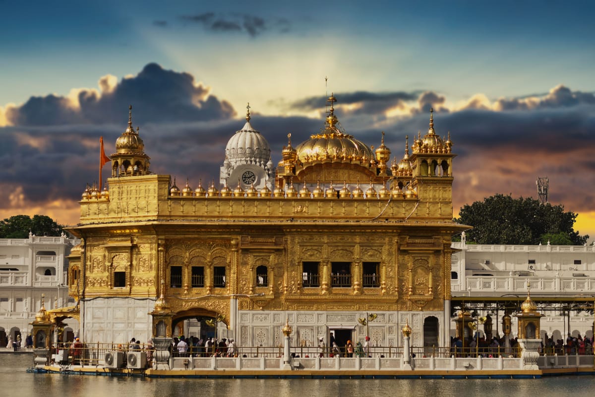 The Golden Temple in Amritsar photographed at dusk, its gilded shrine mirrored in the sacred tank