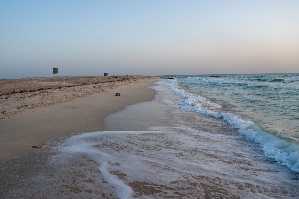 The shoreline at Shivrajpur Beach near Dwarka, waves running up the pale sand under a soft evening sky
