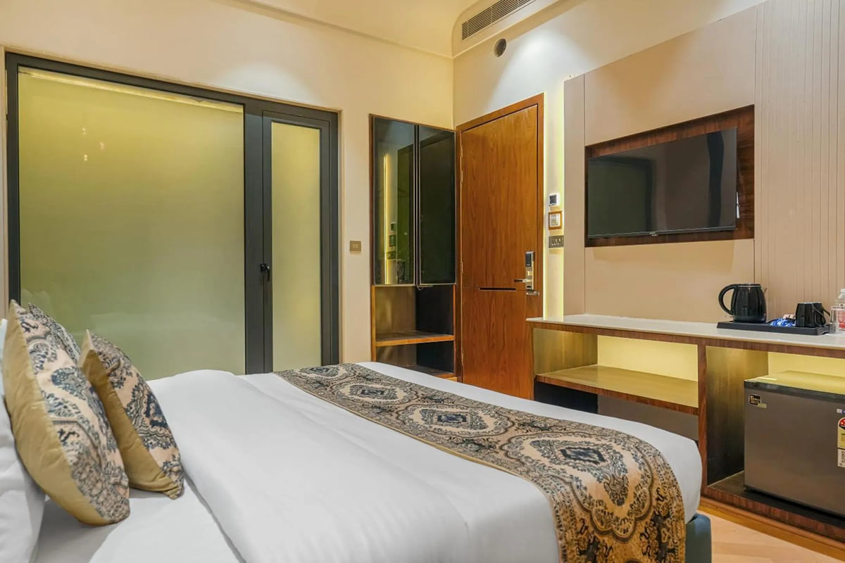 A Deluxe room at Marrion Hotel, with a patterned runner across the bed, a frosted-glass bathroom partition and a television