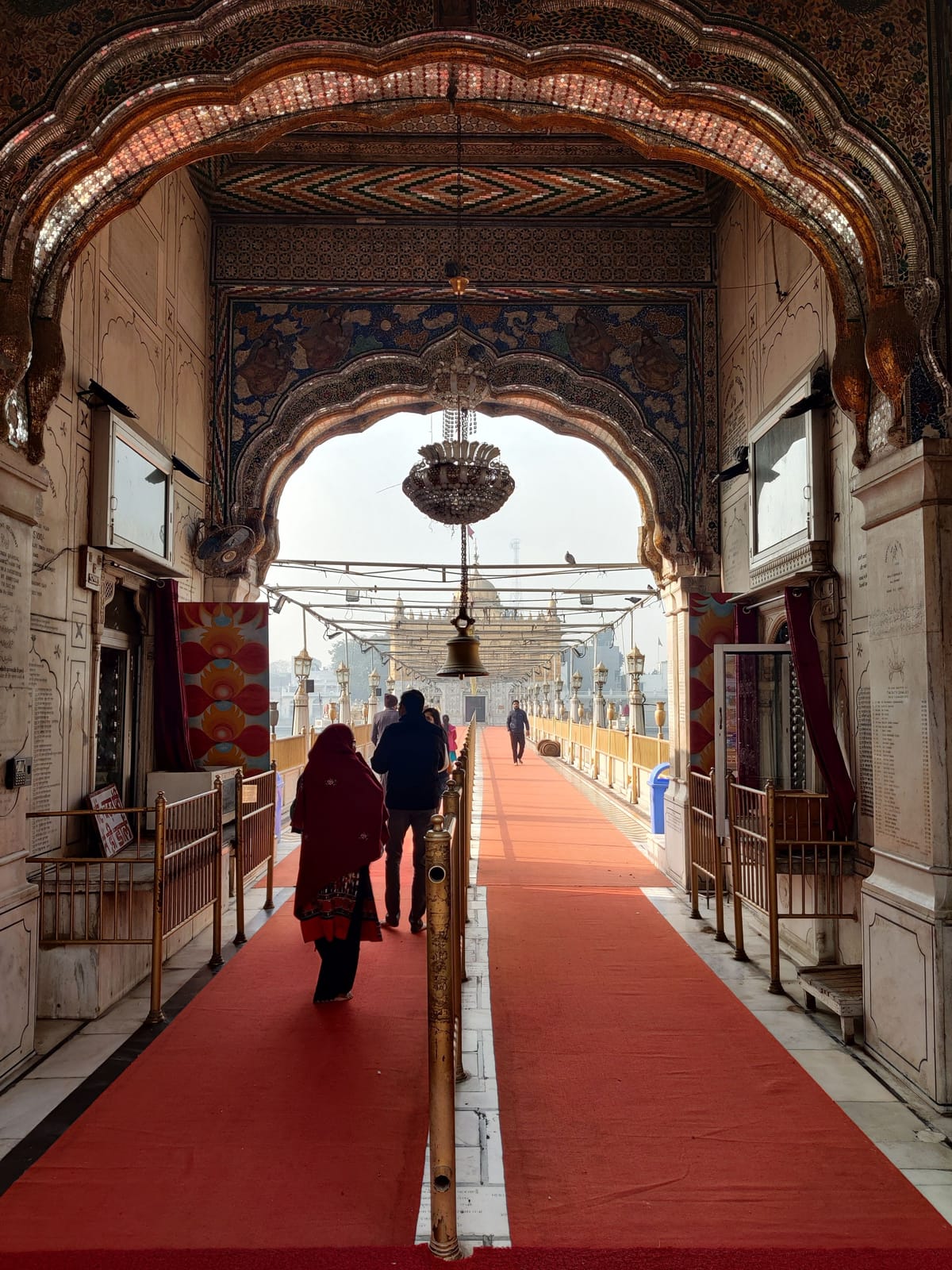 The red-carpeted causeway running through a carved archway towards Durgiana Temple in Amritsar