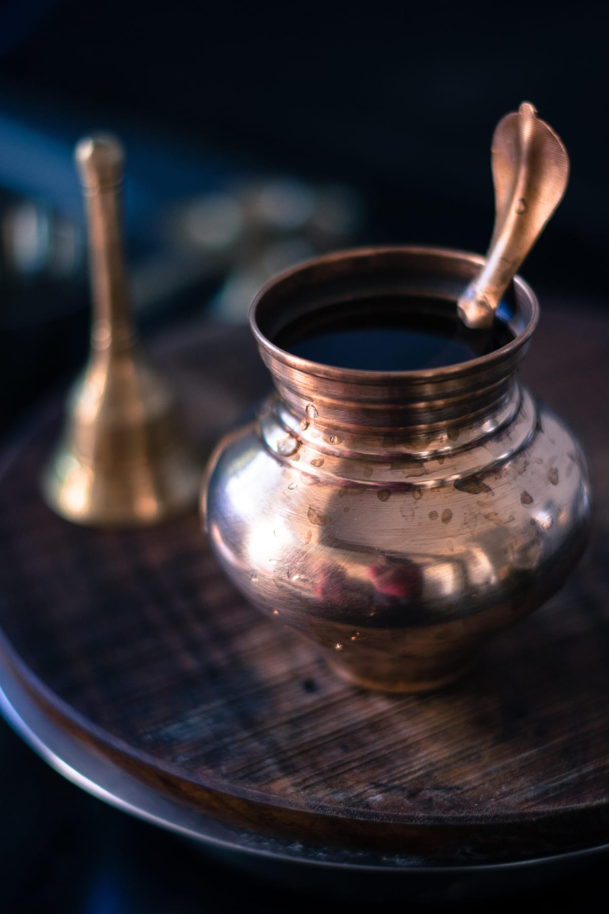 A brass ritual pot and hand bell set out on a temple tray