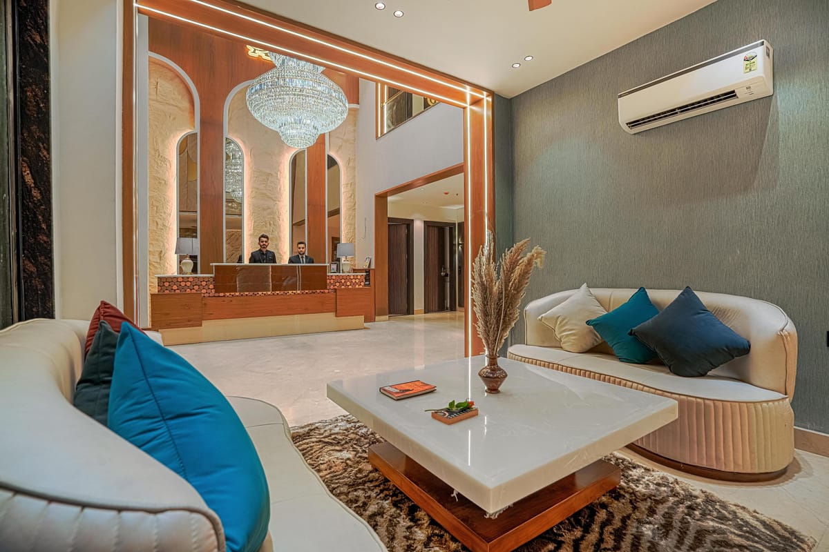 The lounge at Aura Bliss, with curved cream sofas and blue cushions around a low table, a chandelier