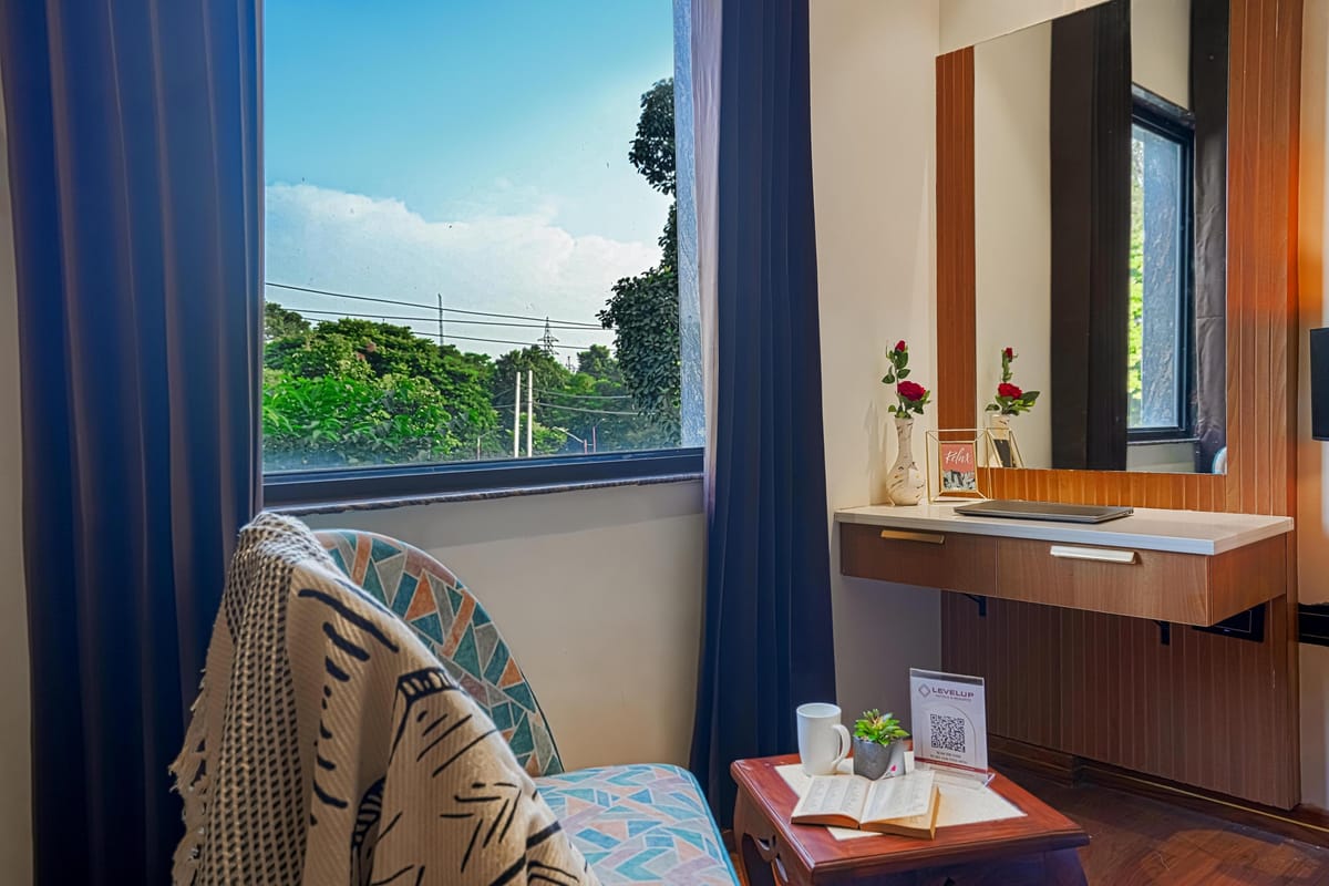 The corner of a Deluxe room at Aura Bliss, with an armchair and throw beside a wide window