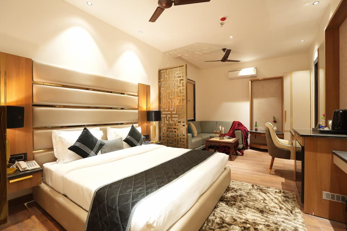 A Suite at Aura Bliss, with a fluted headboard and dark bed runner, a carved screen beside the bed