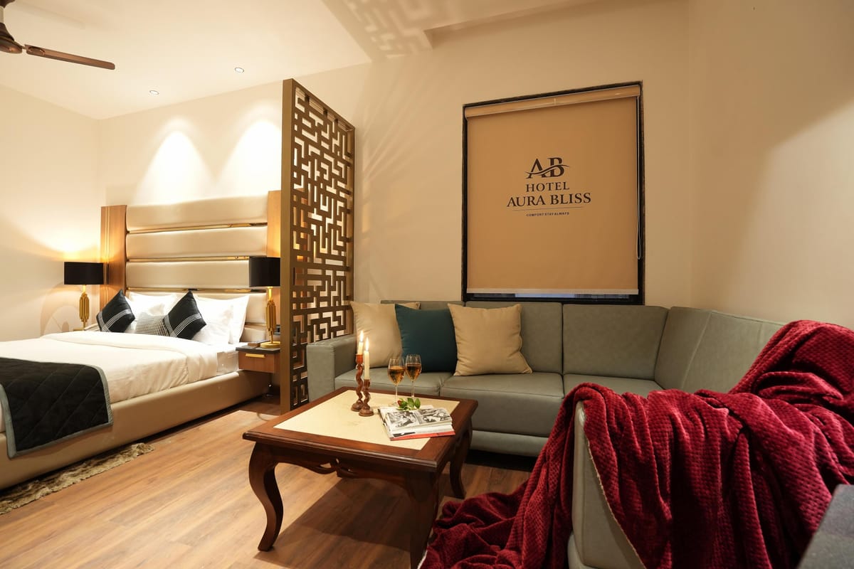 The sitting area of a Suite at Aura Bliss, with an L-shaped sofa and coffee table beside the bed