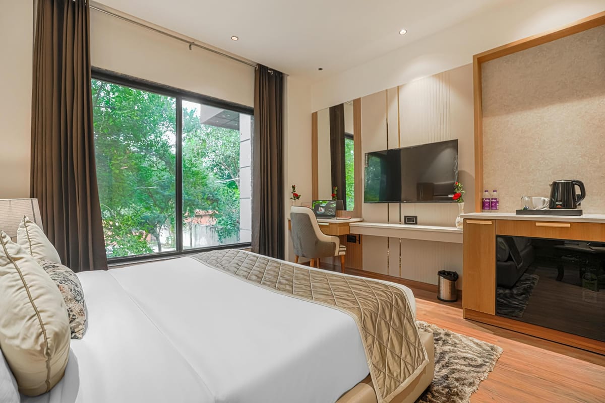 A Superior room at Aura Bliss, with a long desk and kettle beneath a wall-mounted television, an office chair