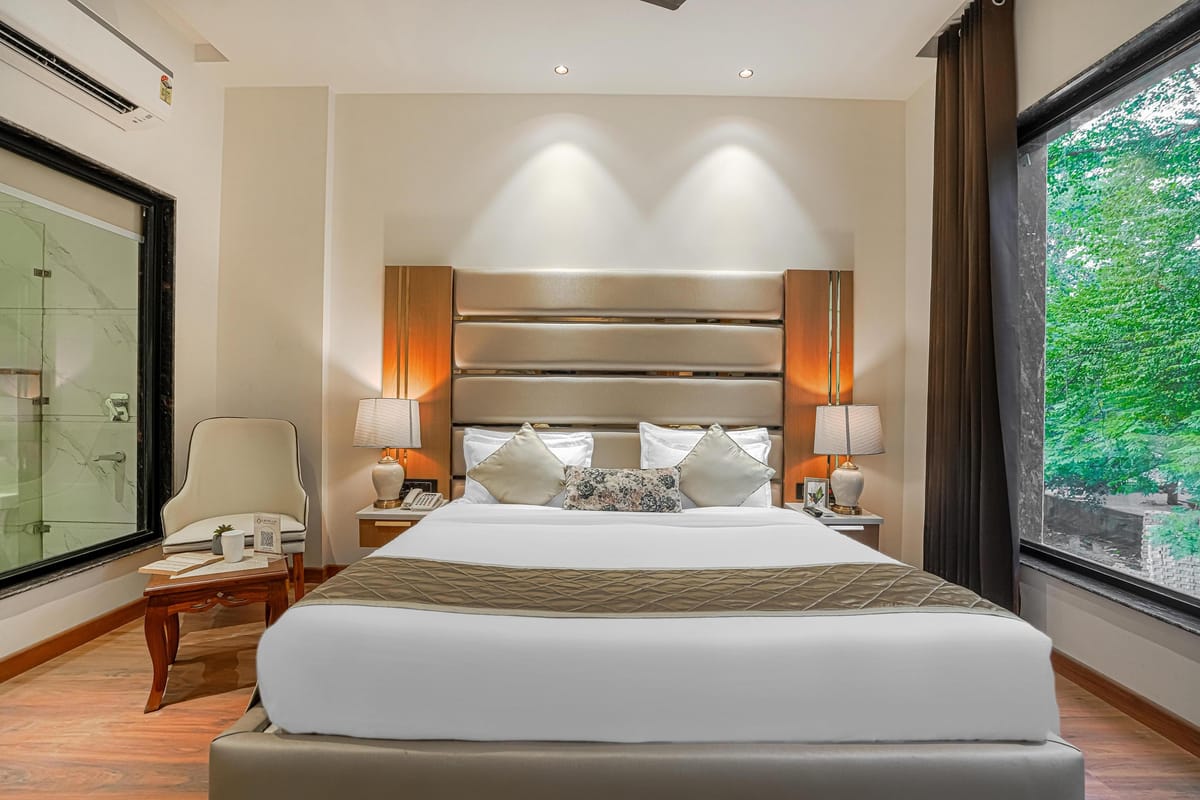A Superior room at Aura Bliss, with a padded headboard, bedside lamps, an armchair by the window