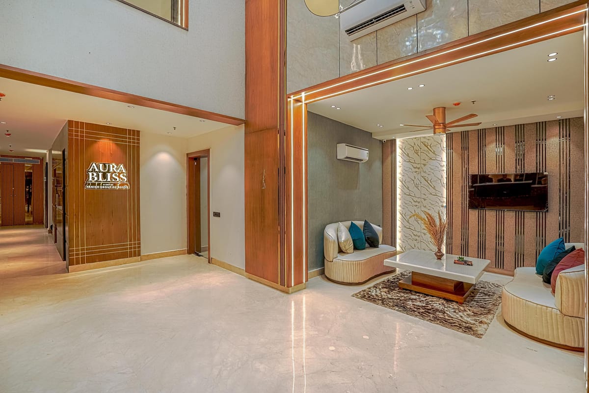 A second lounge area at Aura Bliss, with armchairs around a low table, a television on the fluted timber wall