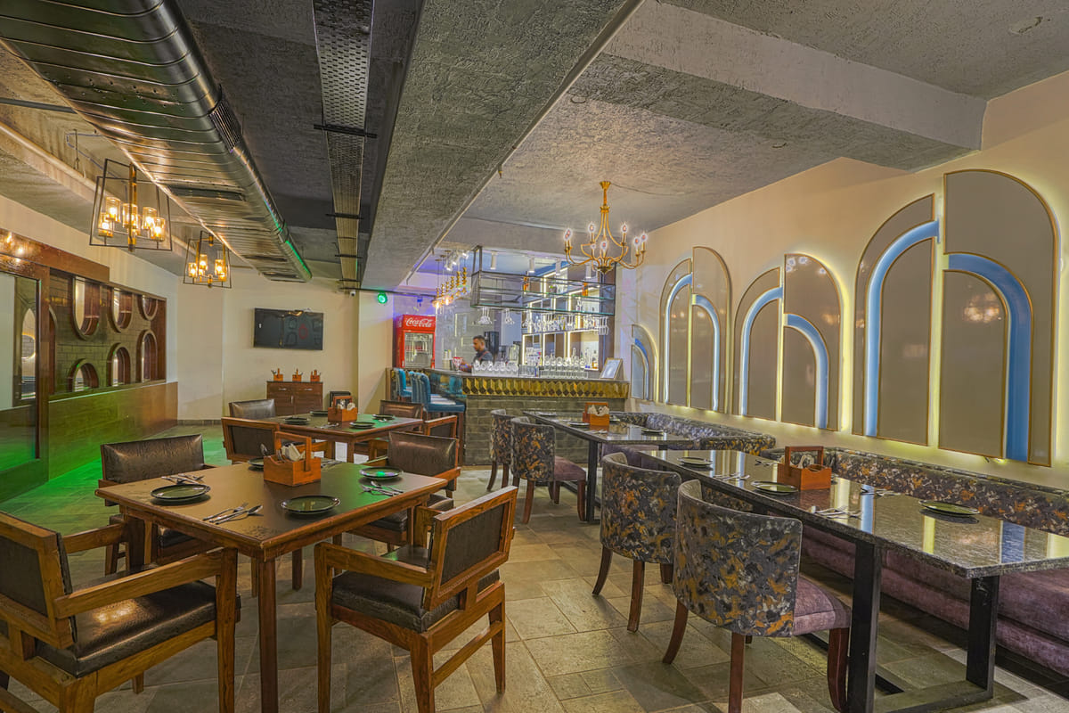 The lounge at Escala Hotel, with a long counter and high stools on one side and wooden tables